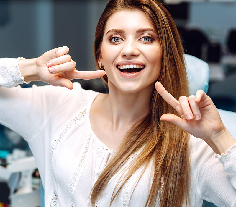 Ragazza che sorride e indica i denti