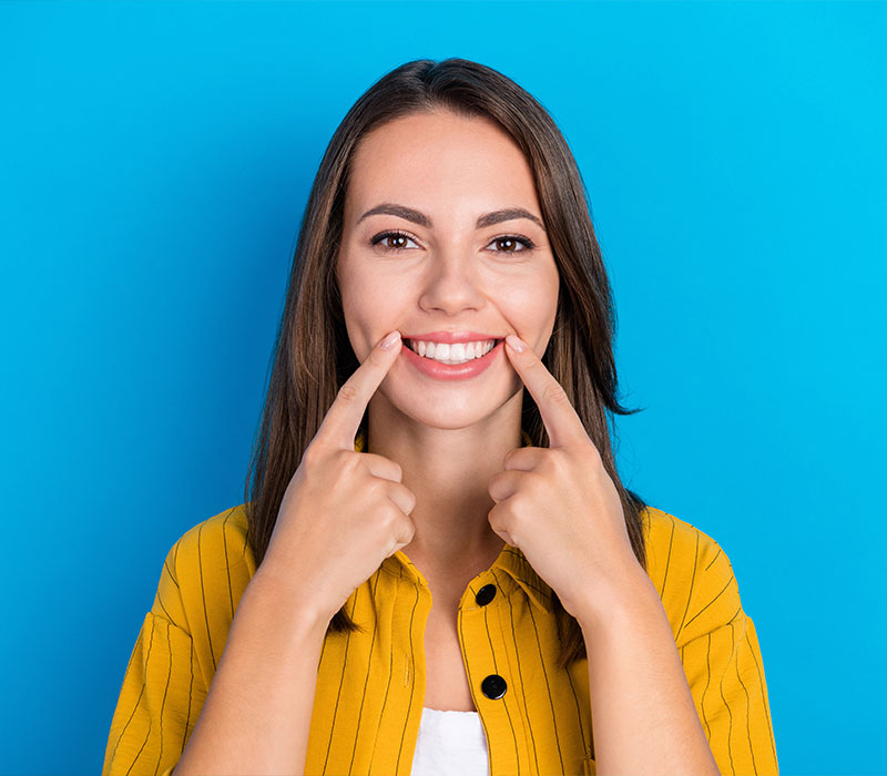 Ragazza che sorride e indica i denti